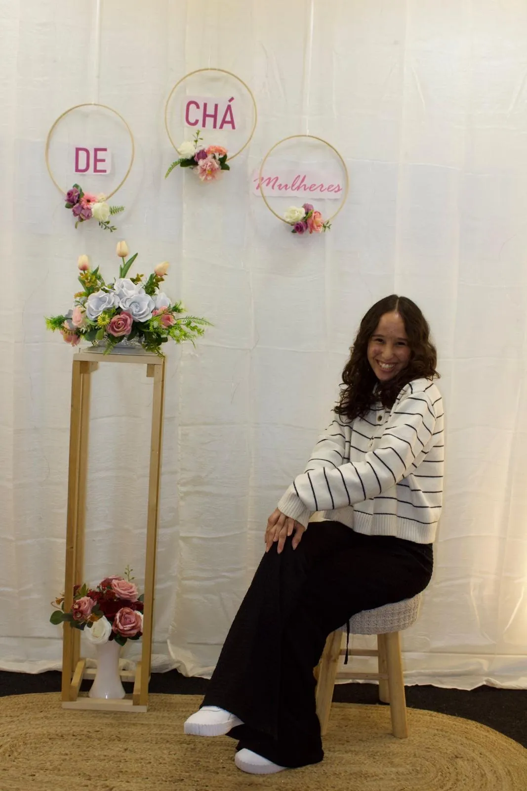 Helena Braga sentada em uma poltrona no consultório, com luz de janela